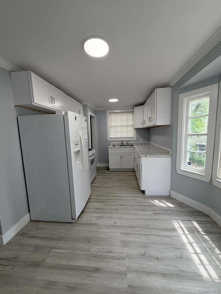 7416 Heyden Detroit, MI 48228 - Photo 8 of 16 Kitchen featuring white appliances, ornamental molding, light countertops, white cabinets, and light wood finished floors
