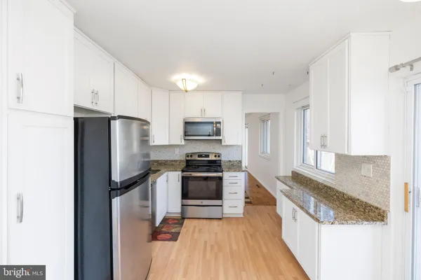 a kitchen with granite countertop a refrigerator stove and oven