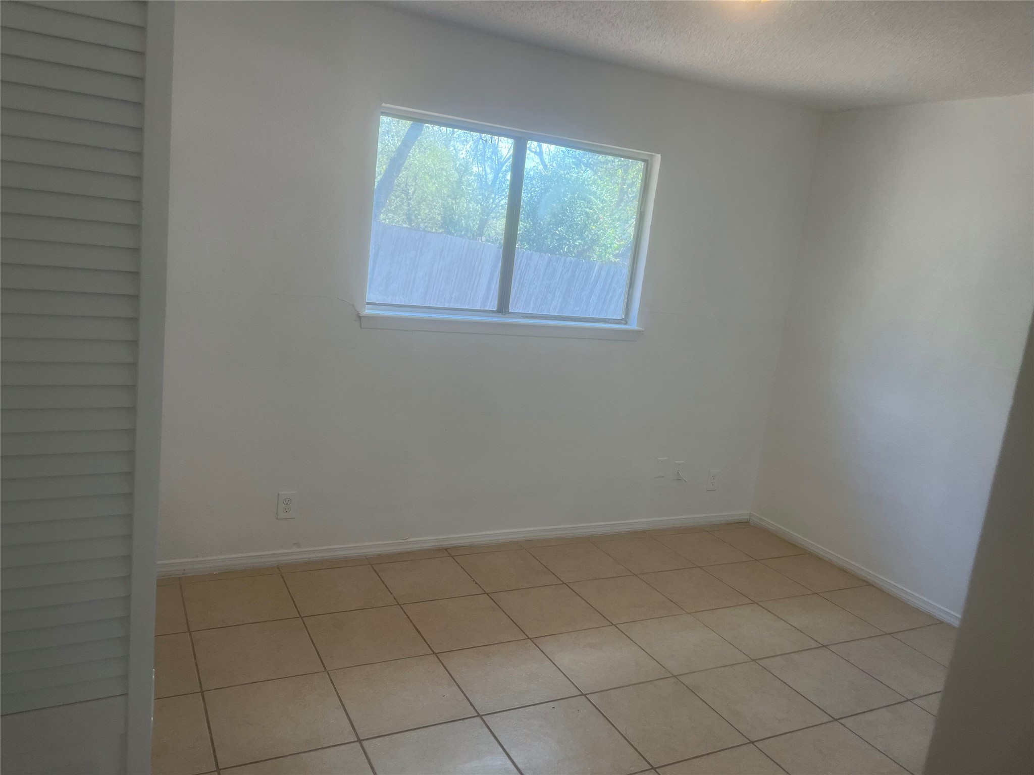 5213 Village Path Austin, TX 78744 - Photo 6 of 7 Easy-to-maintain tile flooring highlights this versatile bedroom space with natural window light.