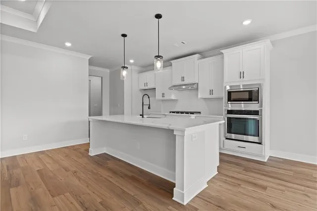 a view of kitchen with stainless steel appliances sink refrigerator and wooden floor