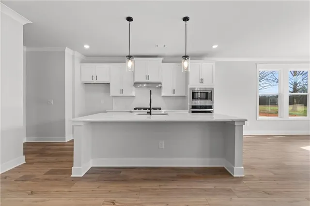 a kitchen with stainless steel appliances granite countertop a sink a stove and a wooden floors