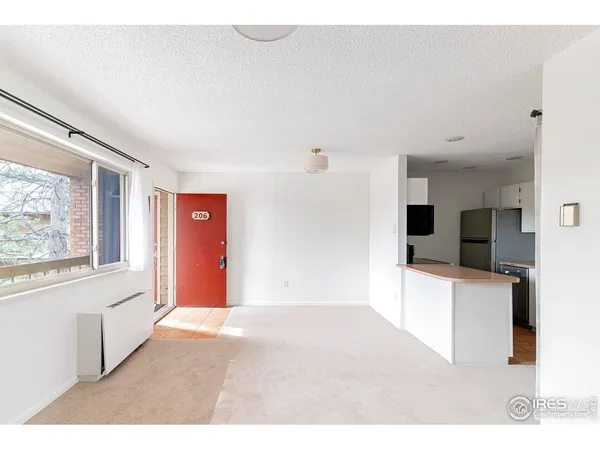 a living room with stainless steel appliances furniture a large window and a kitchen view