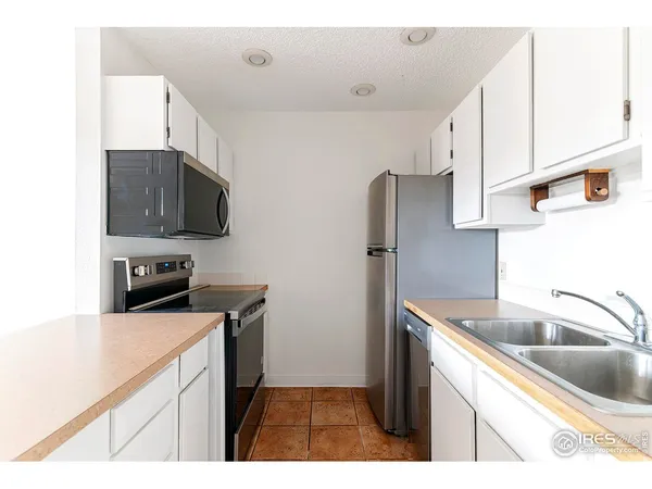 a kitchen with stainless steel appliances a sink a stove a microwave a refrigerator a counter space and cabinets