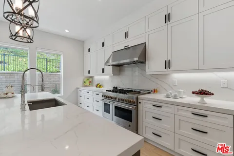 a kitchen with granite countertop a sink a stove and cabinets