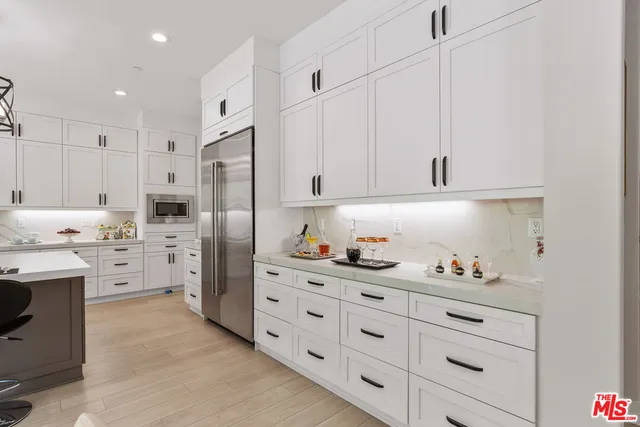 a kitchen with white cabinets and refrigerator