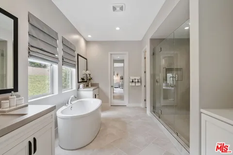 a bathroom with a tub sink shower and mirror