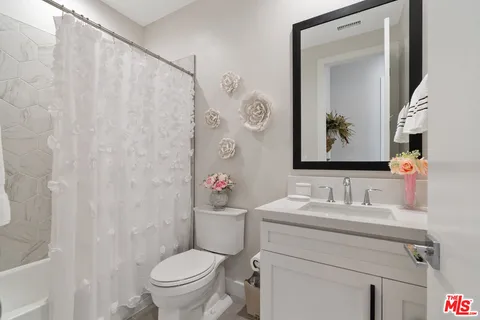 a bathroom with a toilet sink vanity and mirror