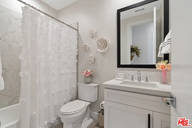 a bathroom with a toilet sink vanity and mirror