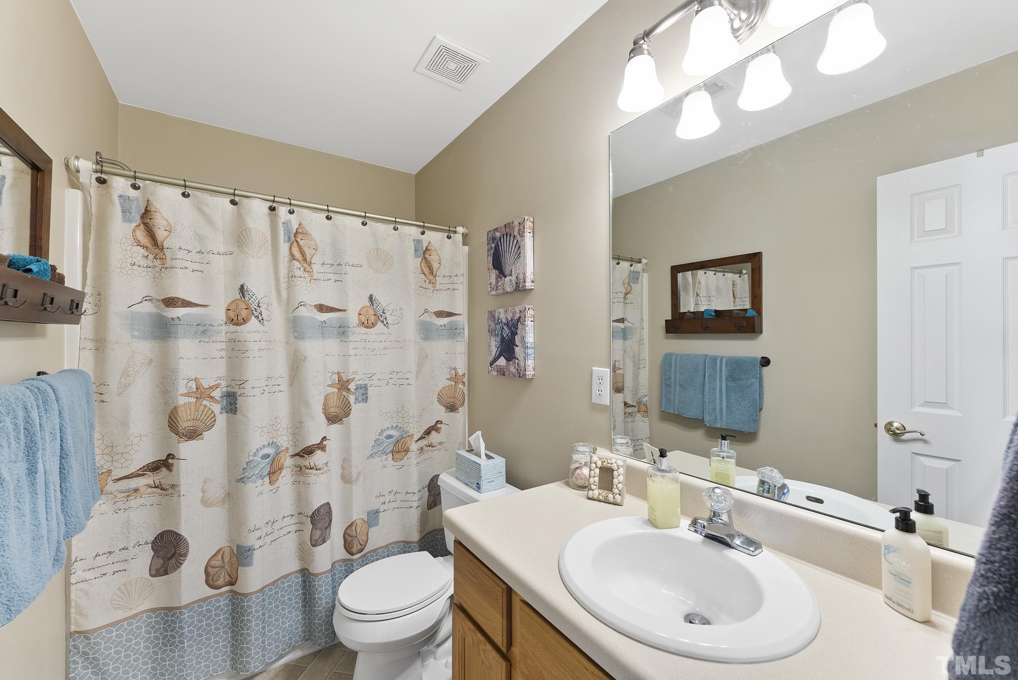 5016 Village Lawn Drive Raleigh, NC 27613 - Photo 20 of 27 a bathroom with a sink toilet a mirror a vanity and shower