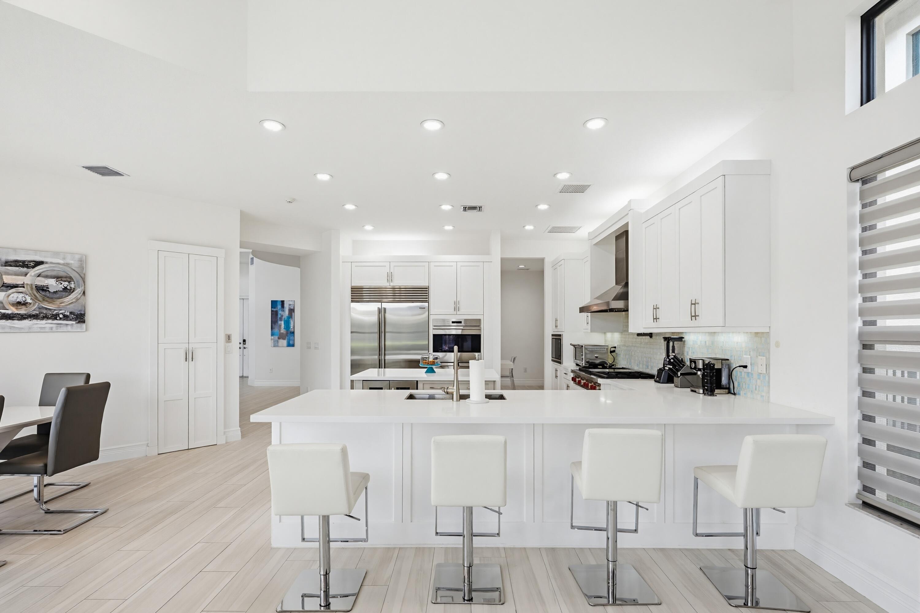 9801 Rennes Lane Delray Beach, FL 33446 - Photo 16 of 77 a kitchen with stainless steel appliances kitchen island granite countertop a stove a sink a dining table and chairs