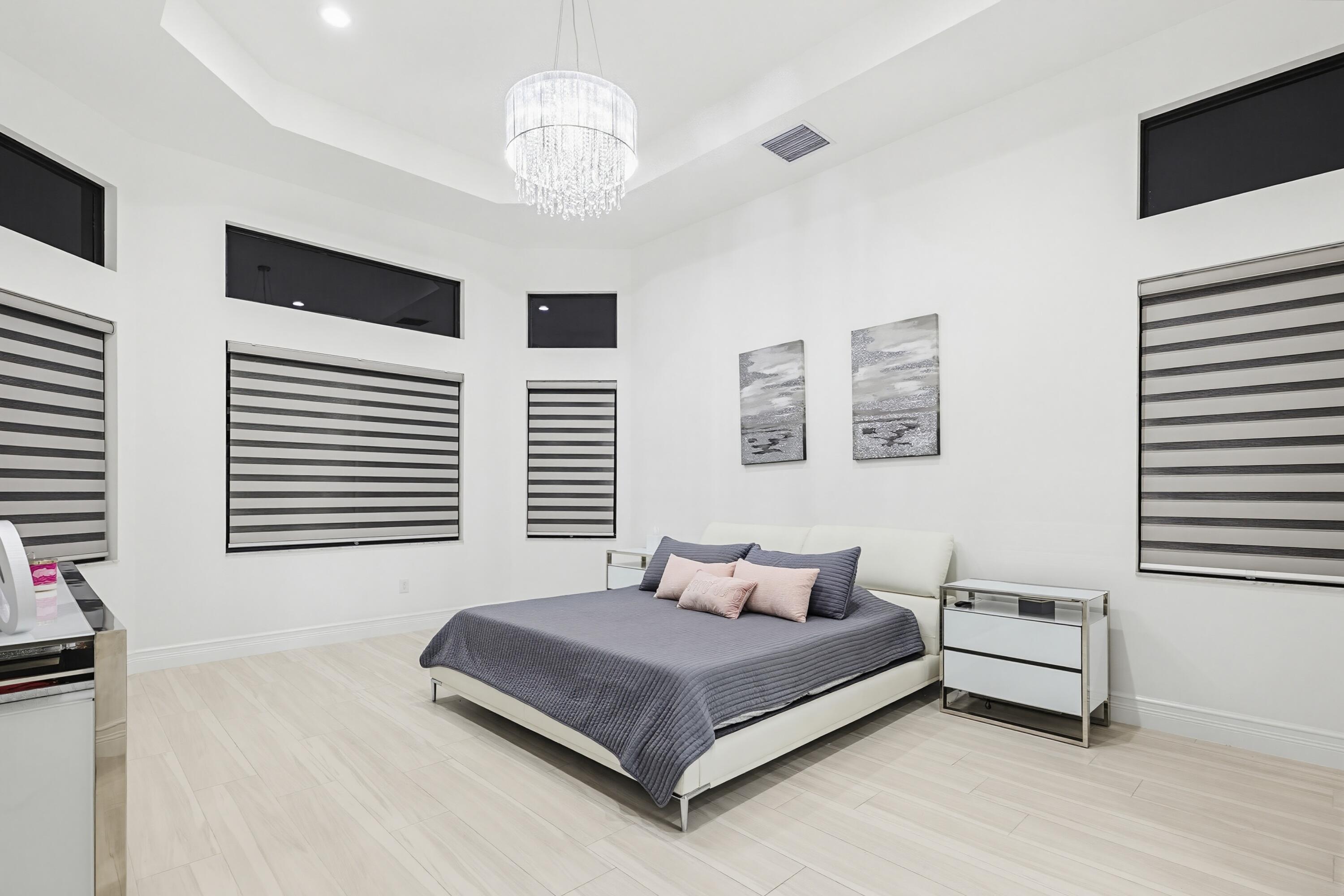 9801 Rennes Lane Delray Beach, FL 33446 - Photo 25 of 77 a bedroom with a large bed and a flat tv screen on dresser