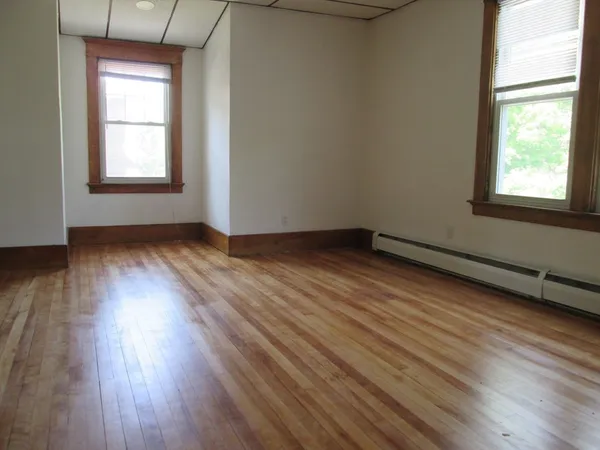 an empty room with wooden floor and windows