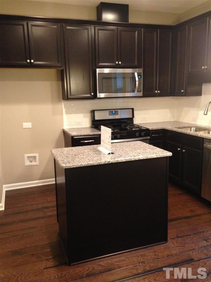690 Wickham Ridge Road, Unit 141 Apex, NC 27539 - Photo 11 of 25 a kitchen with granite countertop wood cabinets and black appliances