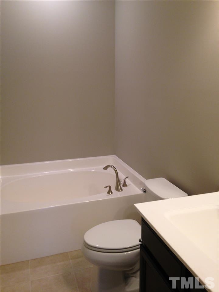 690 Wickham Ridge Road, Unit 141 Apex, NC 27539 - Photo 17 of 25 a bathroom with a sink a toilet and bathtub