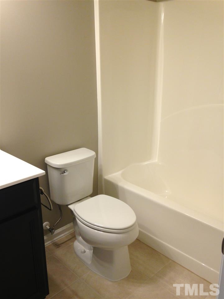 690 Wickham Ridge Road, Unit 141 Apex, NC 27539 - Photo 21 of 25 a white toilet sitting next to a bath tub