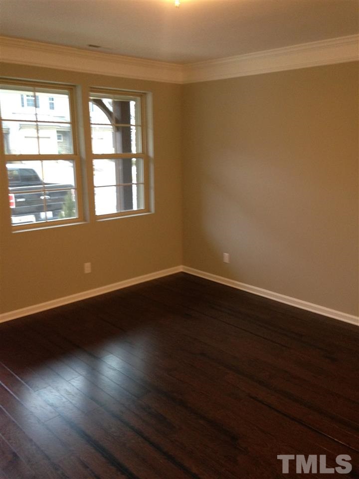 690 Wickham Ridge Road, Unit 141 Apex, NC 27539 - Photo 5 of 25 an empty room with wooden floor and windows
