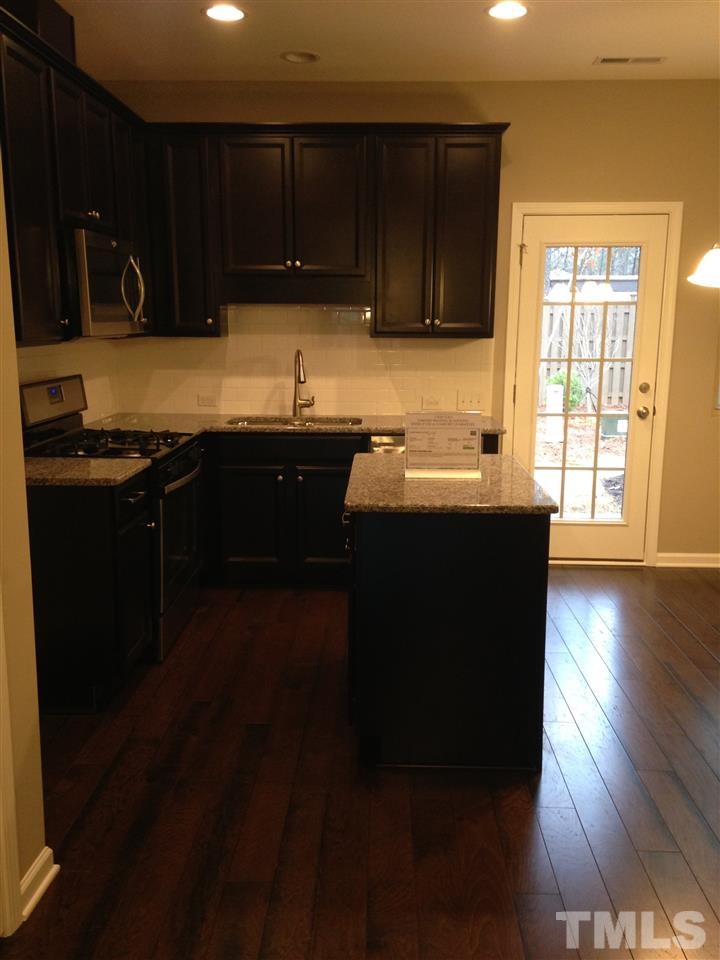690 Wickham Ridge Road, Unit 141 Apex, NC 27539 - Photo 9 of 25 a kitchen with a sink a stove and cabinets