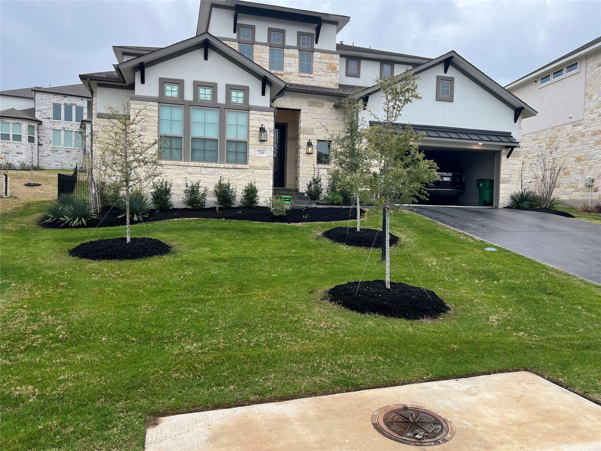 View of front of home featuring stone siding, driveway, stucco siding, a garage, and a front yard