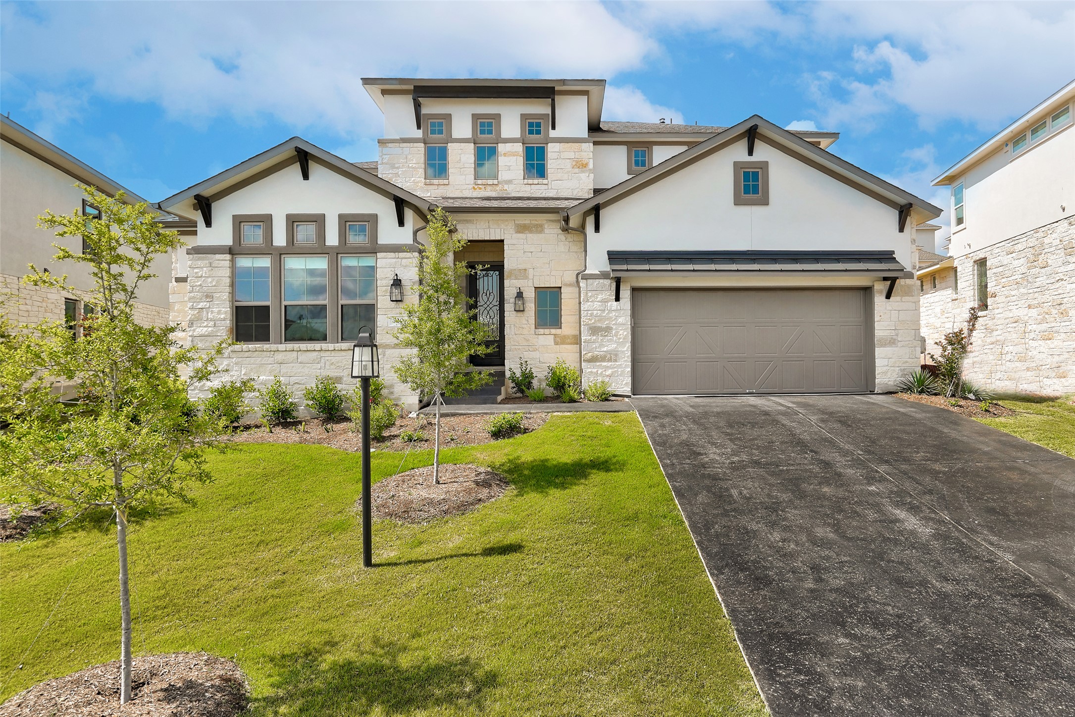 View of front of house featuring stone siding, stucco siding, concrete driveway, a front yard, and a garage
