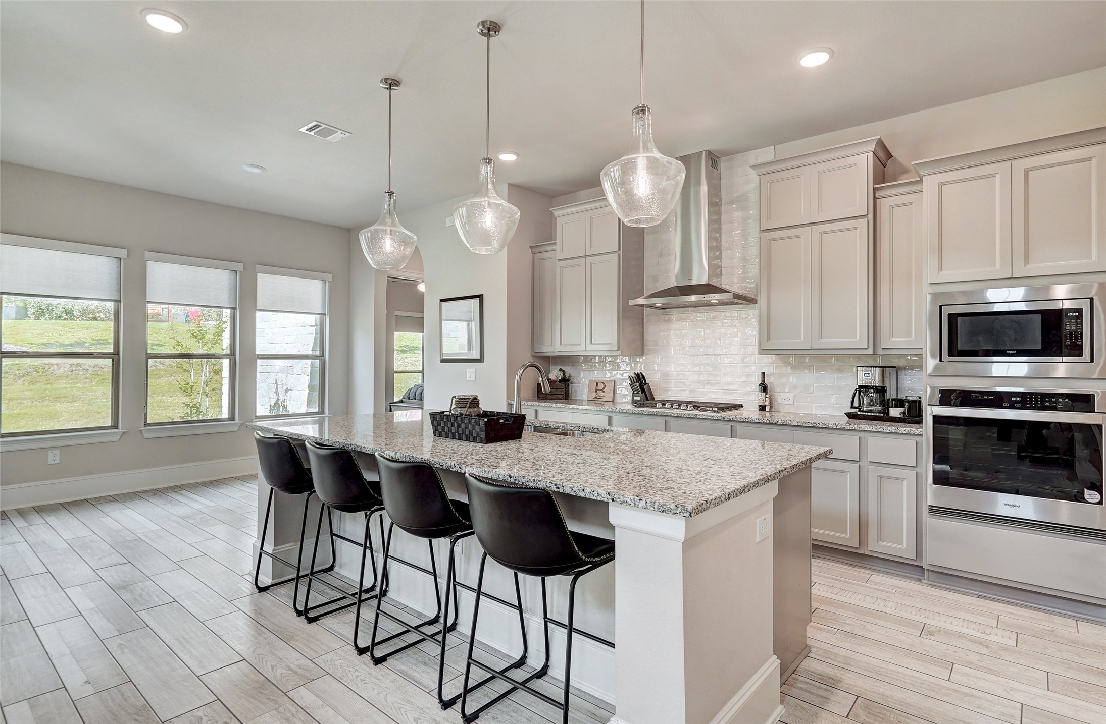 720 Rawson Bend Austin, TX 78738 - Photo 12 of 40 Kitchen with stainless steel appliances, a breakfast bar, wall chimney range hood, backsplash, and wood finish floors