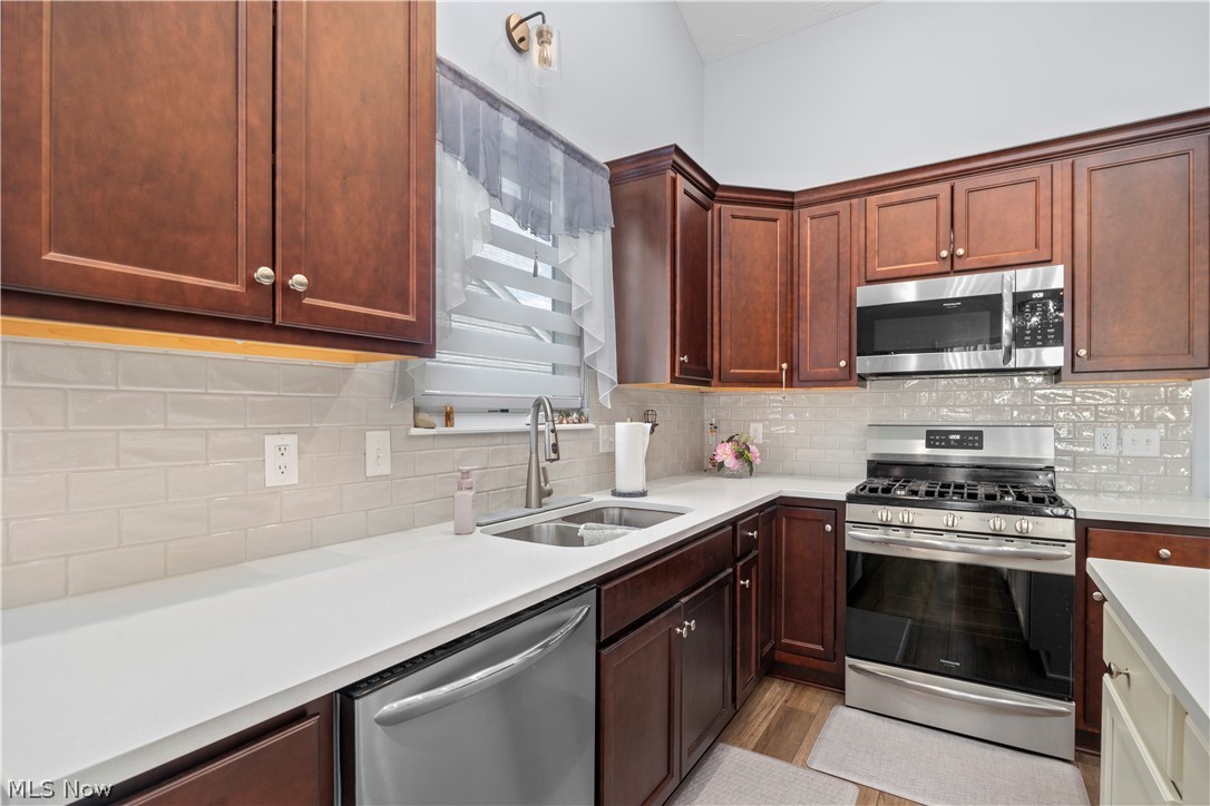 109 West Spring Drive Elyria, OH 44035 - Photo 20 of 46 Kitchen featuring dark wood cabinetry, light countertops, stainless steel appliances, and a subway tile backsplash