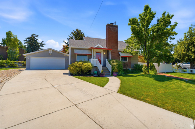 1925 South Main Street Bountiful, UT 84010 - Photo 7 of 48 Exterior featuring a brick chimney, a two-car garage, a concrete driveway, a manicured lawn, and mature trees