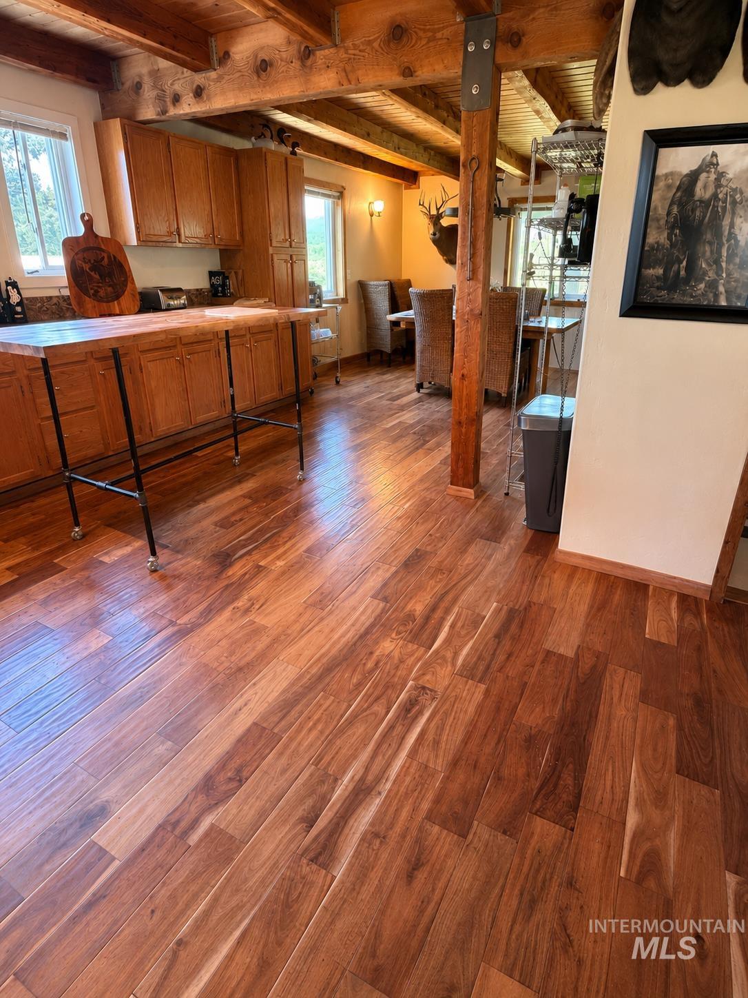 40 Atkin Lane Cascade, ID 83611 - Photo 17 of 46 Interior featuring wood-finish flooring, a brick hearth with a freestanding stove, exposed wood beam ceilings, and a wood-paneled accent wall