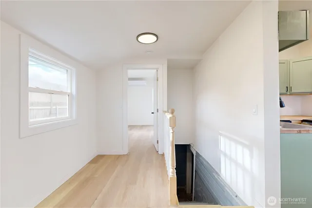 a view of hallway with window and wooden floor