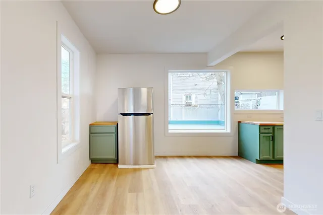 an empty room with windows and refrigerator