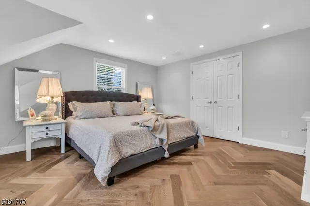 a bedroom with a large bed and wooden floor