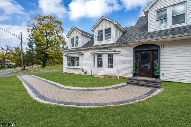 a view of a white house with a small yard and potted plants
