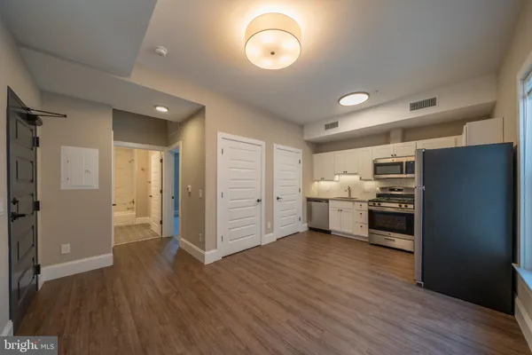 a view of a kitchen with a sink refrigerator and wooden floor