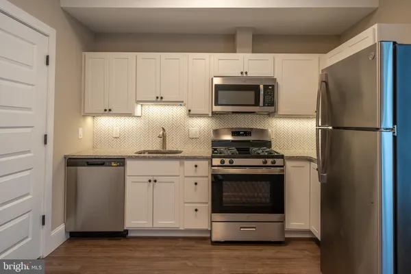 a kitchen with stainless steel appliances granite countertop a refrigerator stove and white cabinets