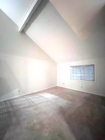 an empty room with windows and refrigerator