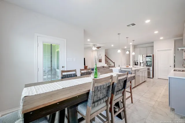 a dining area with stainless steel appliances kitchen island granite countertop a table chairs and a refrigerator