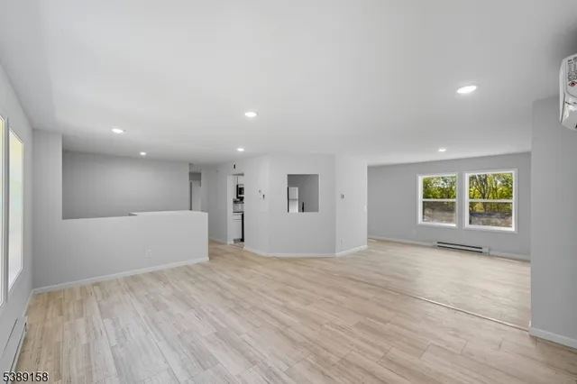 a view of an empty room with a window and wooden floor