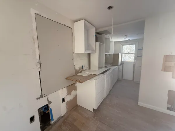 a large white kitchen with cabinets a sink and a window