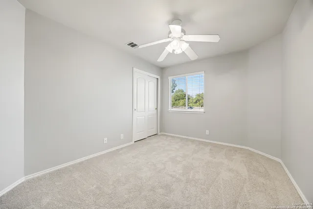 an empty room with windows and fan