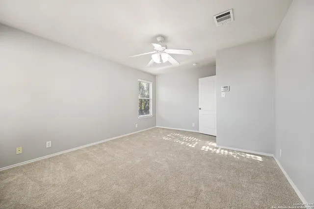 an empty room with a window and a ceiling fan