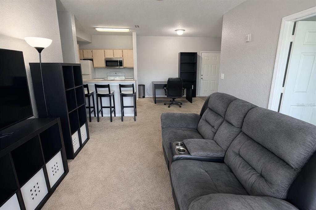 5483 Vineland Road, Unit 10301 Orlando, FL 32811 - Photo 5 of 13 a living room with furniture and a flat screen tv