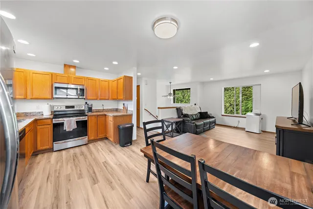 a kitchen with stainless steel appliances a table wooden floor and a view of living room