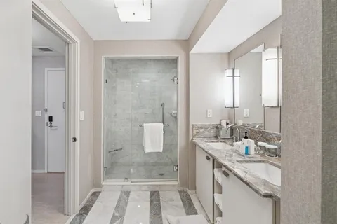 a bathroom with a granite countertop sink a mirror and a shower