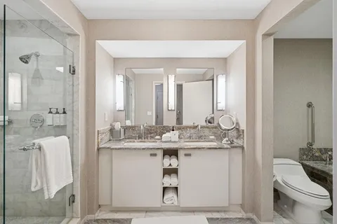 a bathroom with a granite countertop sink a toilet and a mirror