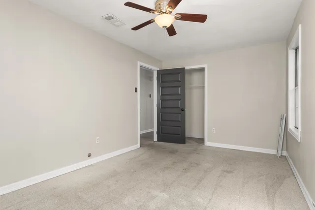 an empty room with closet and ceiling fan