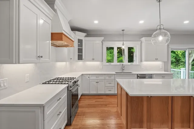 a kitchen with a stove a sink a center island and windows