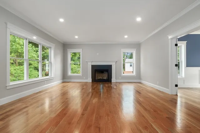 an empty room with wooden floor fireplace and windows