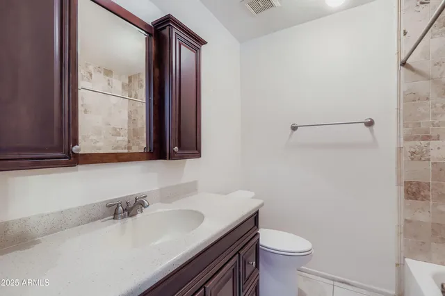 a bathroom with a granite countertop sink toilet and mirror