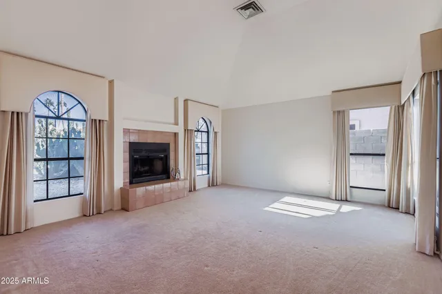 an empty room with windows and fireplace