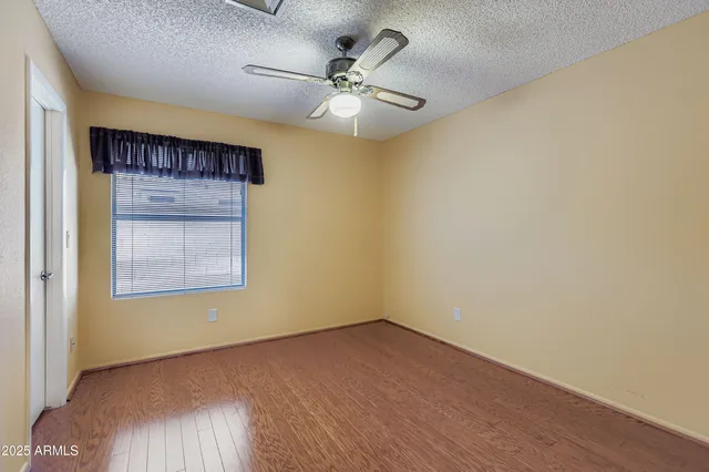 an empty room with a ceiling fan and wooden floor