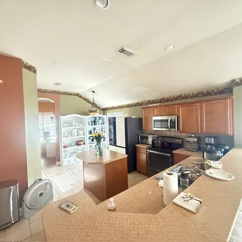 a living room with stainless steel appliances kitchen island granite countertop a table and chairs in it